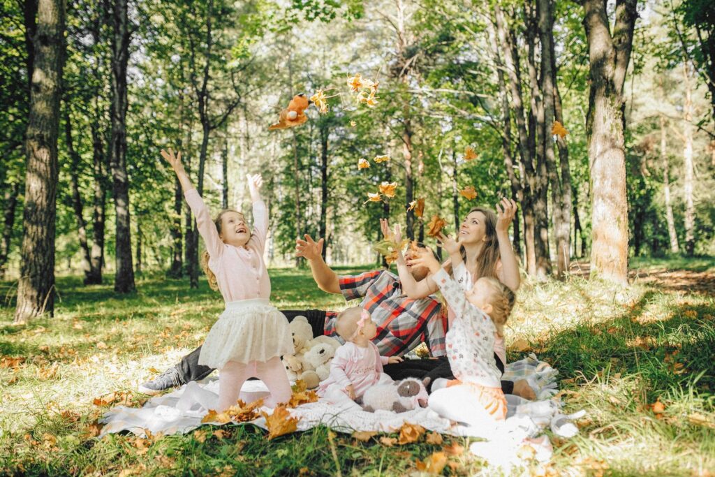 Family enjoying a playful moment in an autumn forest, beneath falling leaves.